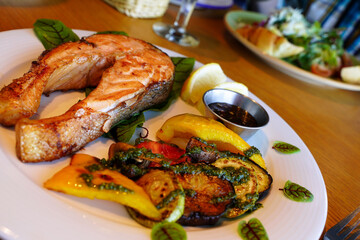 Grilled salmon with vegetables, lemon and pesto sauce. Serving the dish. Shallow depth of field - 522579119