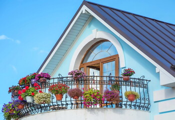 Attic with an openwork elegant balcony decorated with flowers - obrazy, fototapety, plakaty