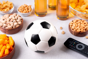 Beer and snack on gray table with football ball, football game night food