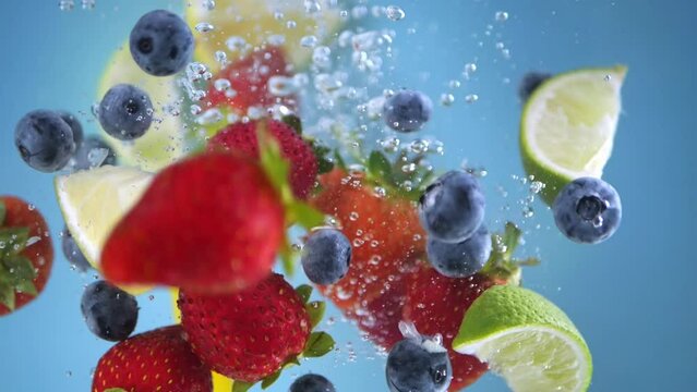 Super slow motion shot of fruit falling into the water with splashing. Blue background.
