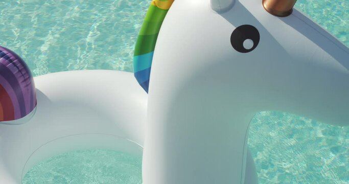 Close-up Inflatable colorful white unicorn at the swimming pool.Pool Beach Vacation travel concept with inflatable unicorn float toy mattress by luxury swimming pool. Luxury lifestyle summer holidays