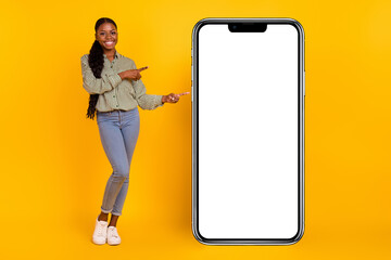 Full size photo of attractive cheerful girl indicate fingers empty space blank isolated on yellow...