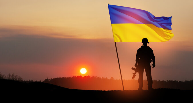 Flag of Ukraine with silhouette of soldier against the sunrise or sunset. Concept - armed forces of Ukraine. Relationship between Ukraine and Russia.