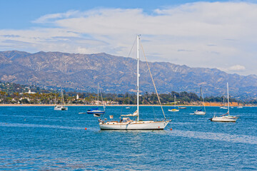  Santa Barbara harbor. Yachts moored in harbor, ocean view, and mountains and cloudy sky on background