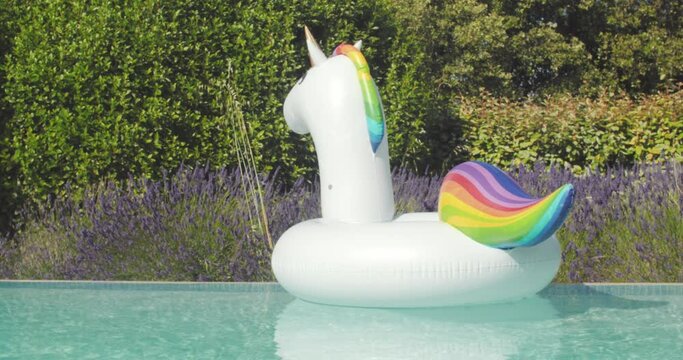 Inflatable colorful white unicorn at the swimming pool.Pool Beach Vacation travel concept with inflatable unicorn float toy mattress by luxury swimming pool. Luxury lifestyle summer holidays