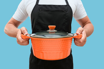 Large pan for cooking in the hands of a cook isolated on a blue background. The concept of cooking