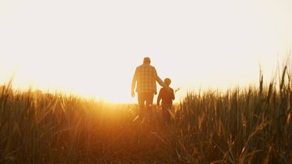 Farmer and his son in front of a sunset agricultural landscape. Man and a boy in a countryside field. Fatherhood, country life, farming and country lifestyle. - obrazy, fototapety, plakaty