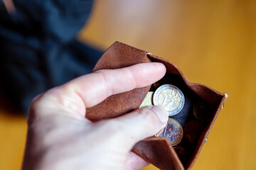 Eine Hand hält eine geöffnete Geldbörse mit Euro Münzen. - obrazy, fototapety, plakaty