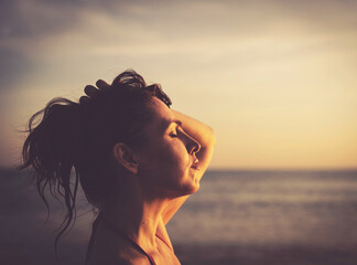 the last sunrays. 45-50 y.o. brunette woman on sunset beach, retro tones closeup portrait
