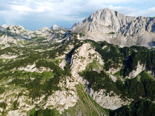 Aerial drone view of mountain range. Green forest  in early summer. Cliffs and rocks in nature.  