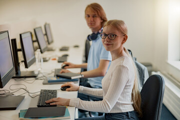 Focused university student using computer studying in computer room and looking camera