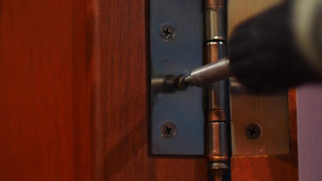 close-up fixing the hinge on interior doors with a screwdriver. installation of interior doors concept. repair work in the house, replacing doors. selective focus