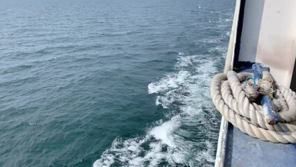 Stern waves with white foam tips on greyish blue sea water, photo taken from aboard ship. Selective focus