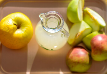 Apple cider vinegar in a glass bottle and slices of apples.