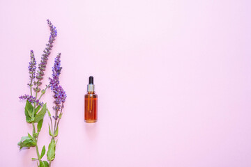 Flat lay composition with lavender flowers and natural cosmetics on a pink background.Bottle with pipette