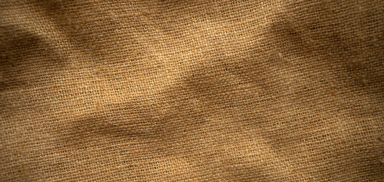Photo of the texture of brown burlap. Fabric from a coffee bag. Brown background made of fabric for text.
