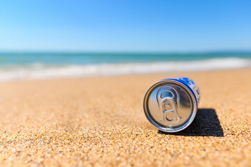 Can of cold refreshing drink on the sandy shore.