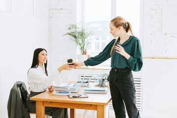 two young business women professionals in formal wear clothes work in modern office using laptop, tablet, brainstorm and search for solutions together, confident independent Asian girl solves problems