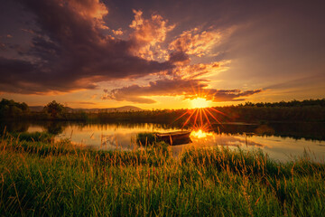 Krajobraz wodny. Widok na jezioro i zachód słońca. Piękny zachód słońca nad jeziorem ze starą łodzią i bezchmurnym niebem w tle, Polska - obrazy, fototapety, plakaty