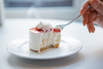 Red and white cake being cut with fork in female hand.