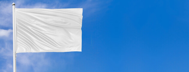 White flag waving in the wind on flagpole against the sky with clouds on sunny day, closeup....