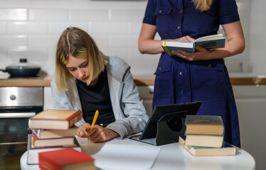 Teenage girl and her mother doing schoolwork at home.
