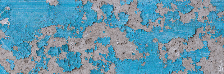 Peeling paint on the wall. Panorama of a concrete wall with old cracked flaking paint. Weathered rough painted surface with patterns of cracks and peeling. Wide panoramic grunge texture for background