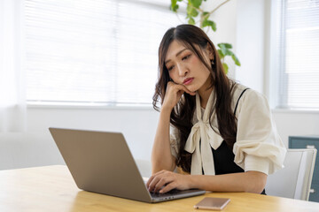 A worried Japanese woman by remote work in the small office