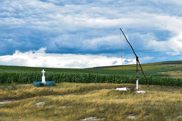 Fototapeta na wymiar Old fountain and stone crucifixion in field, rural, summer, Moldovan landscape