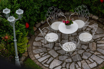 Iron chairs and table on stone patio in garden