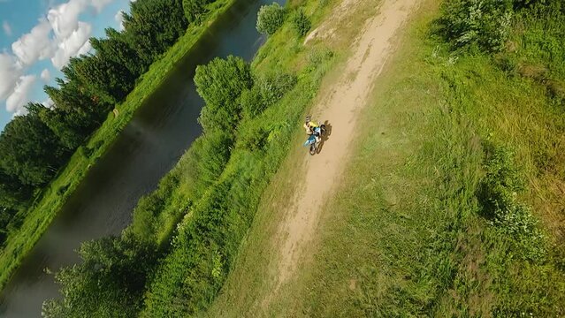 A motorcyclist jumps on a motocross track and drives on. Quadrotor filming