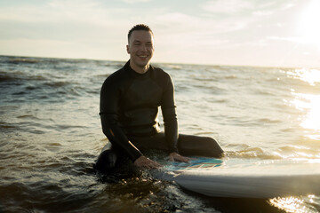A male surfer rides the waves in the sea on a surfboard in a wetsuit