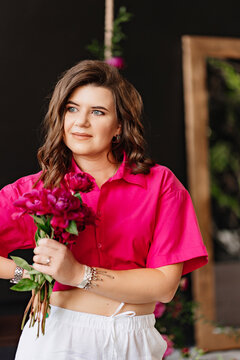 a brunette woman in a pink blouse with peonies