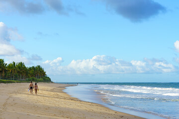 casal eterno caminhando sobre a areia de uma linda praia vazia no litoral nordestino  - obrazy, fototapety, plakaty