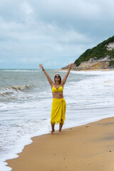 mulher usando roupa de praia amarela, feliz e contente aproveitando as férias em praia do nordeste brasileiro 