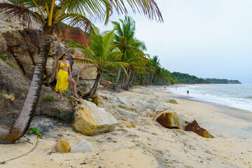 mulher usando roupa de praia amarela, feliz e contente aproveitando as férias em praia do nordeste...