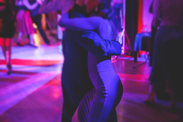 Couples dancing traditional latin argentinian dance milonga in the ballroom, tango salsa bachata kizomba lesson in the red and purple lights, dance festival - obrazy, fototapety, plakaty