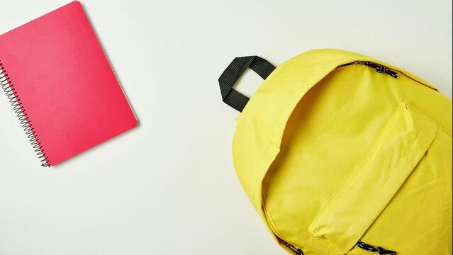 stop motion of yellow backpack with school supplies getting inside it
