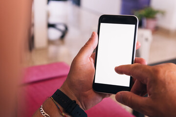 Elderly man using mobile phone in his living room. Hands of elderly person using his phone terminal connected to the internet and consulting his finances and social networks.