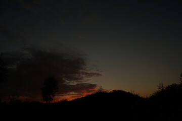 Obraz premium Green meadow under sunset sky with clouds