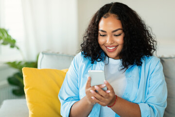Cheerful African American Woman Using Smartphone Sitting At Home - obrazy, fototapety, plakaty
