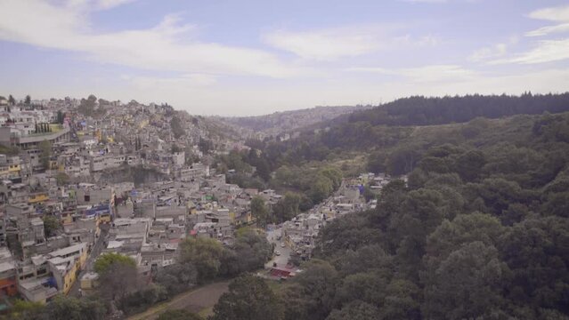 Toma panor&aacute;mica de la periferia de la Ciudad de M&eacute;xico de d&iacute;a. Barrio popular en colina con &aacute;rboles. Casas de ladrillo. 