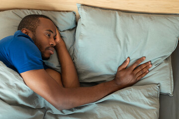 African Man Touching Pillow Suffering From Loneliness After Breakup Indoor