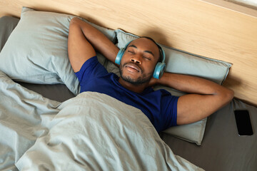 African Guy Sleeping Wearing Headphones Listening To Relaxing Music Indoor