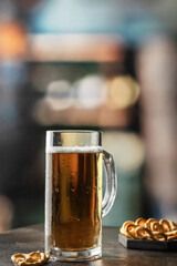 Glass mug of light cold beer with foam with snacks in a pub. Text space