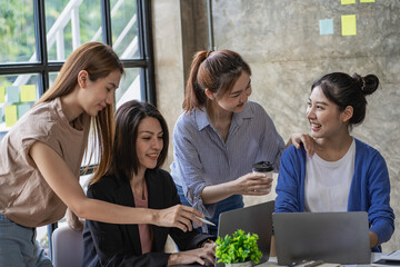 Naklejka premium Young creative team colleague Four women discuss ideas in the boardroom. Group of Asian women during the initiation of a brainstorming session to start an office business.