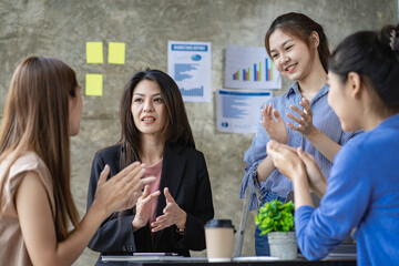 Young creative team colleague Four women discuss ideas in the boardroom. Group of Asian women during the initiation of a brainstorming session to start an office business.
