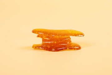 pieces golden cannabis wax resin on yellow background.