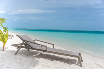 Beautiful tropical beach with white sand and sun lounger on background of turquoise ocean and blue sky with clouds. Luxury resort in Maldives 2022