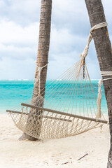 Tropical beach summer relax landscape with beach swing or hammock hang on palm tree over white sand sea beach banner. Vacation summer holiday concept. Luxury romantic travel 